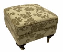 Floral upholstered footstool on brass castors