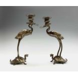 A pair of Japanese patinated bronze candlesticks, early 20th century, each cast as a crane on a