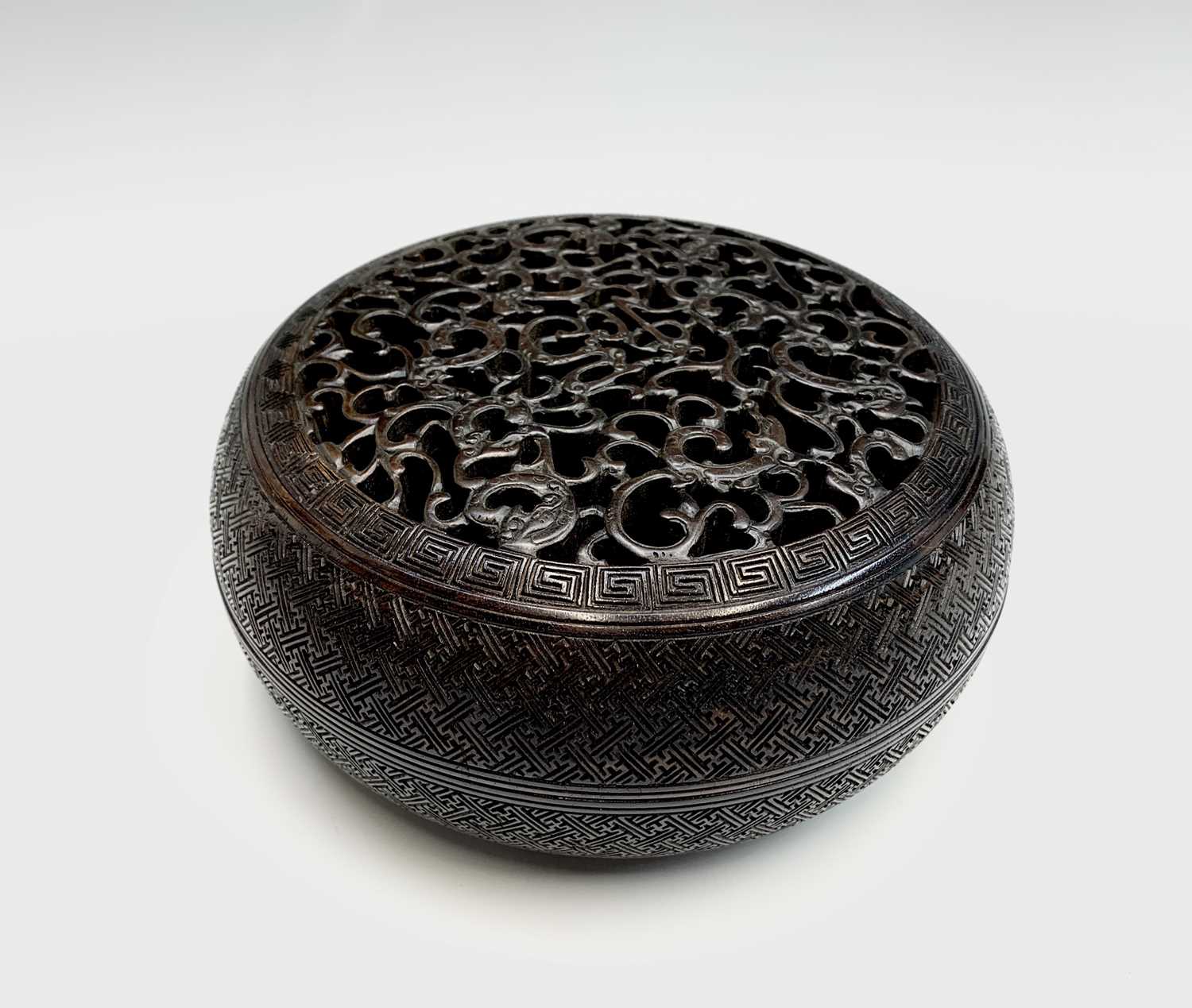 A Chinese Zitan wood circular box and cover, 18th century, the pierced cover carved with nine