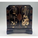 A Japanese gilt and black lacquered table cabinet, early 20th century, the pair of panelled doors