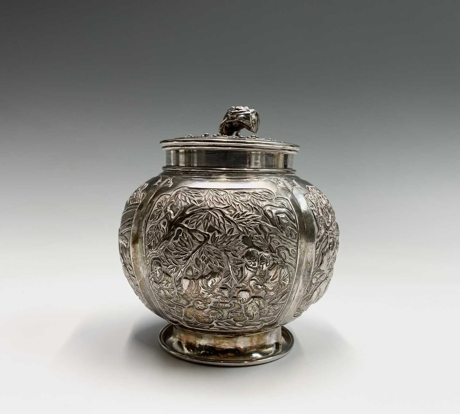 A Chinese silver globular tea caddy, the body with four shaped panels enclosing garden scenes