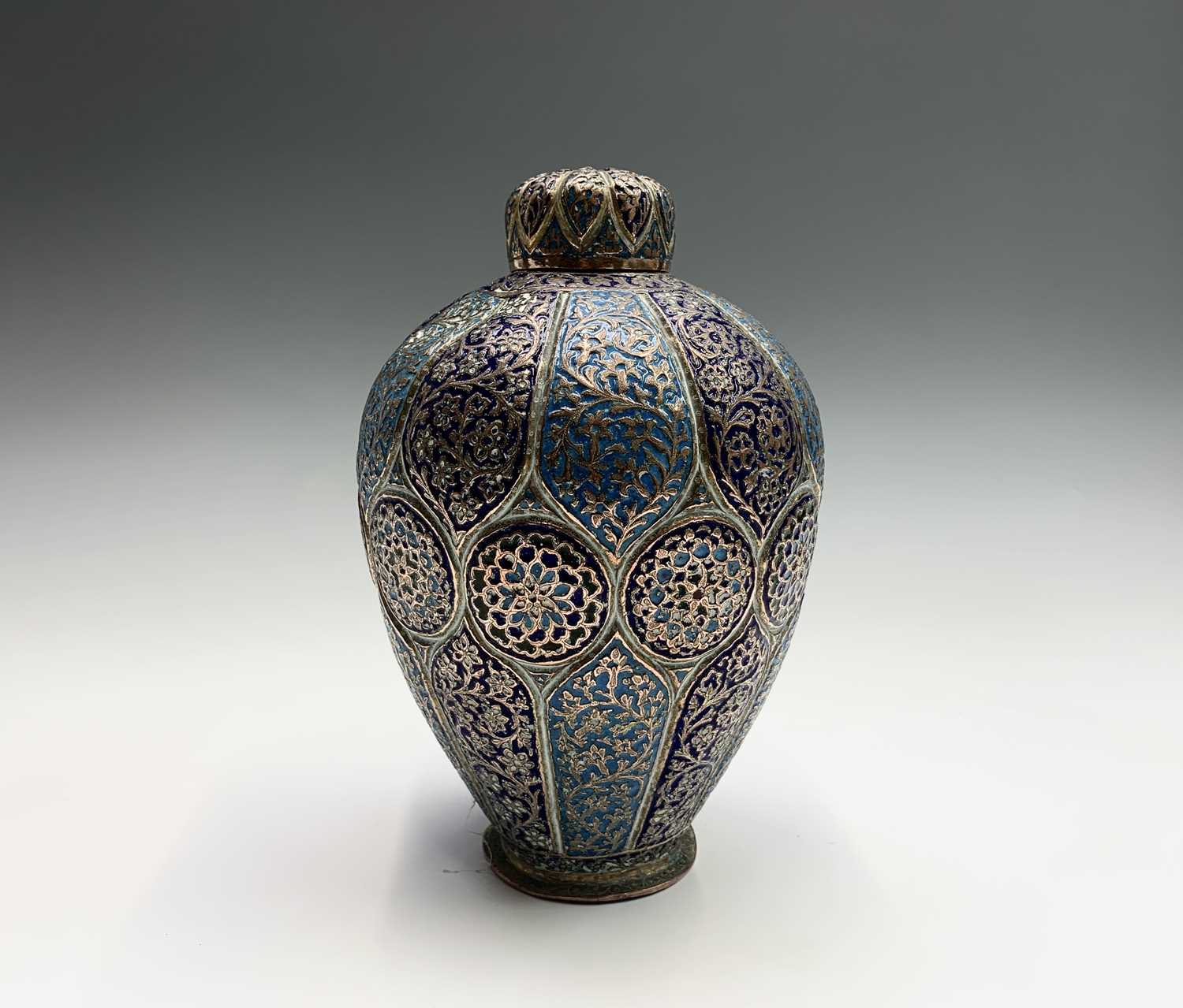 A Persian enamelled copper vase and cover, 19th century, the navy and sky blue panels each enclosing