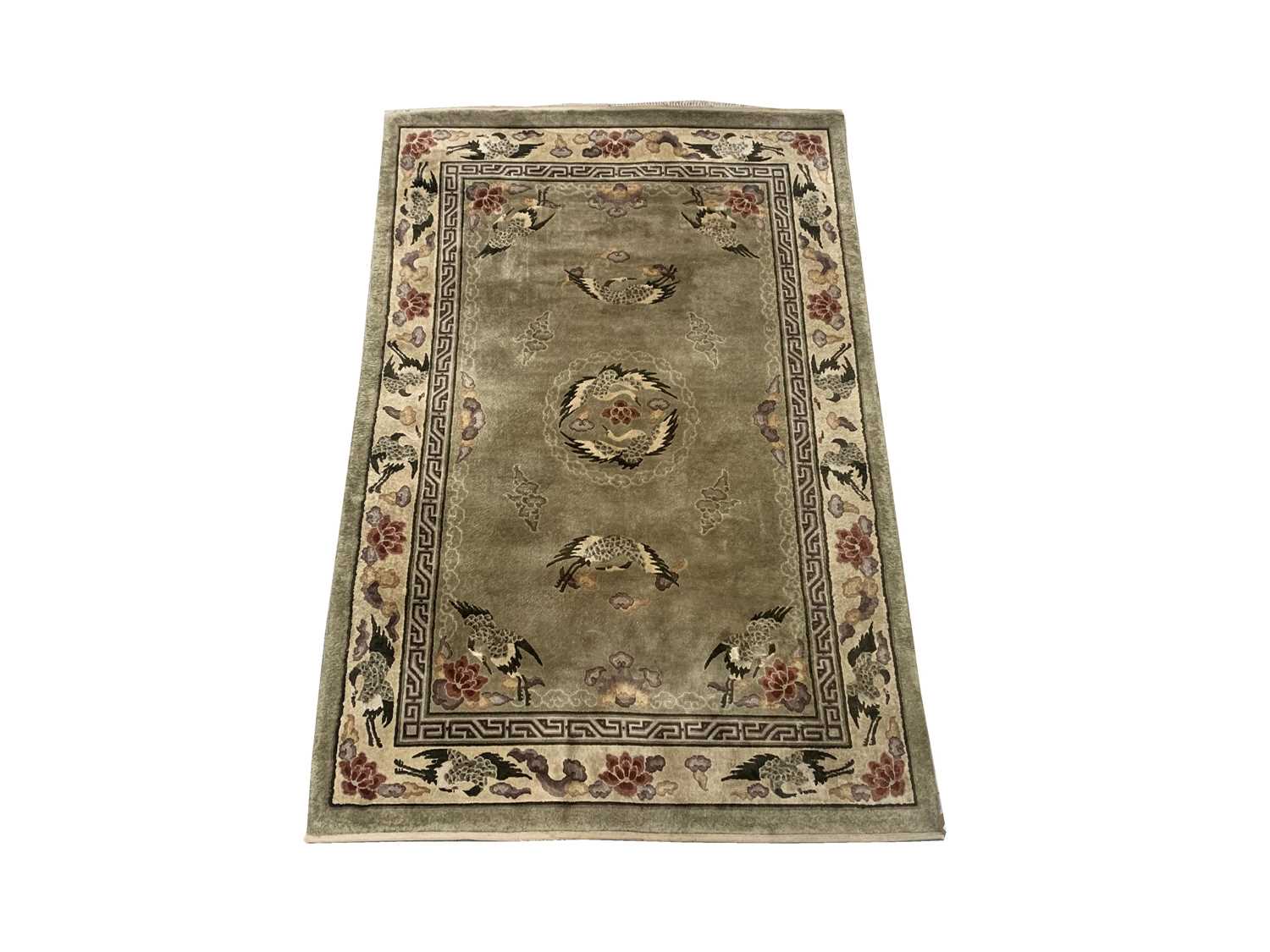 A Chinese 'art silk' rug, the green field with flowers and birds, within an ivory similar border,