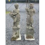 A pair of reconstituted stone garden statues, modelled as a male with a basket of grapes and a