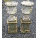 A pair of reconstituted stone garden urns of campana form with classical figural frieze