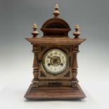 A German walnut and metal mounted mantel clock, with turned finials and cream enamel chapter ring,