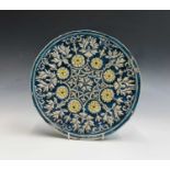 A Middle Eastern pottery plate, probably 19th century, decorated in high relief with flowerheads and
