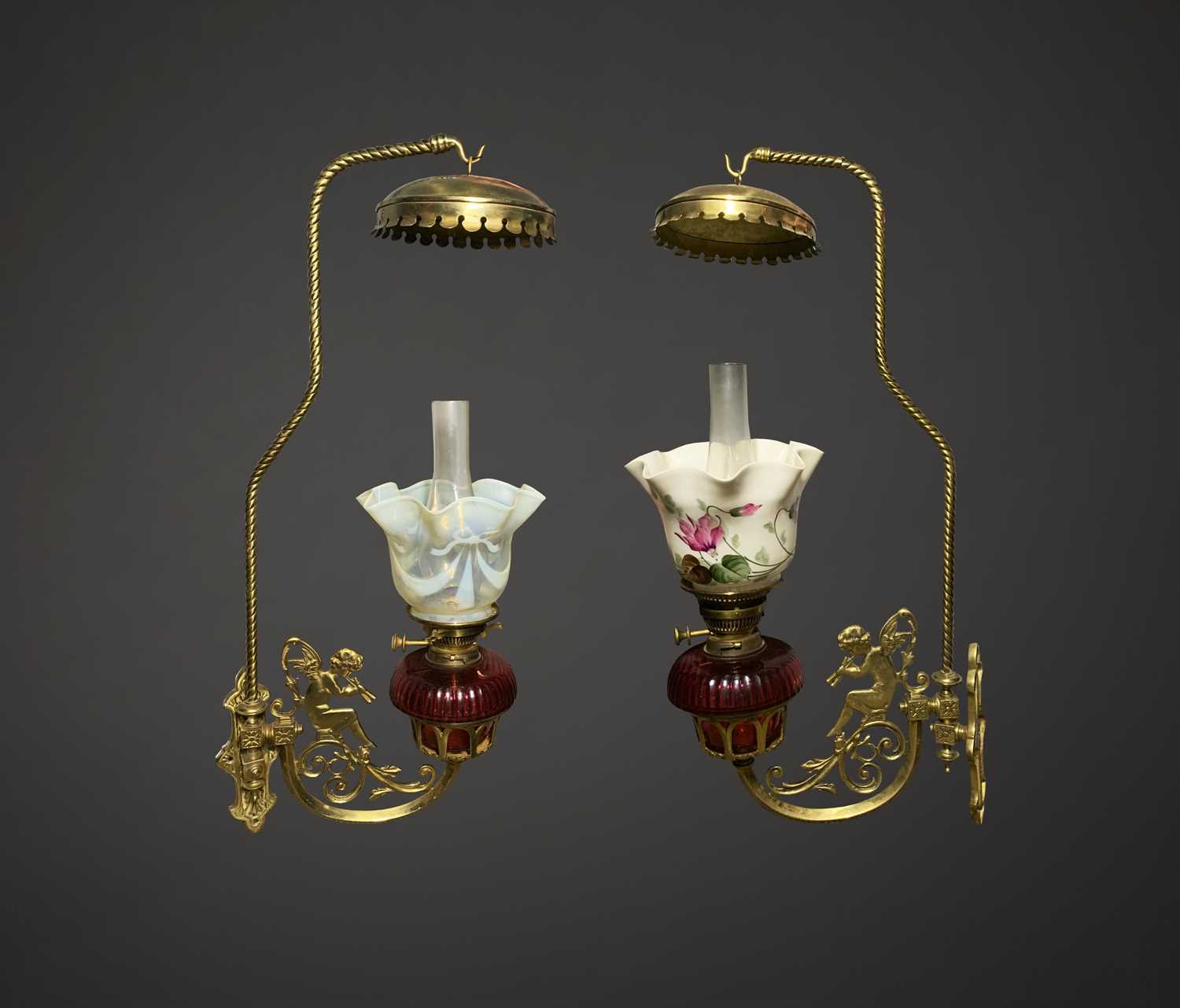 A pair of rare late Victorian Romany wall mounted brass cherub oil lamps, each with cranberry