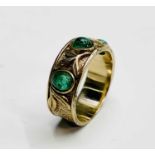 A 9ct gold craft style band ring set with three cabochon emeralds separated by trefoil applied