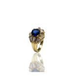 An 18ct gold ring in 1950s style, the principle stone a sapphire of approximately 1.3cts, set within