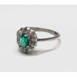 An 18ct white gold emerald and diamond oval cluster ring 2.3gm