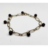 A 9ct gold bracelet with seven garnet beads 4.7gm