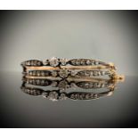 A Victorian high purity gold hinged double bangle set in silver with two trios of diamonds flanked