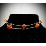 A delicate gold necklace with spaced pierced gold links and carnelian beads 14.9gm