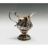 An early George III silver cream jug of pear shape with repoussé decoration by SM possibly Samuel