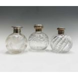 Three spherical glass toilet bottles each with silver lid