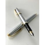 A Sheaffer brushed chrome, gold trim fountain pen and matching ballpoint