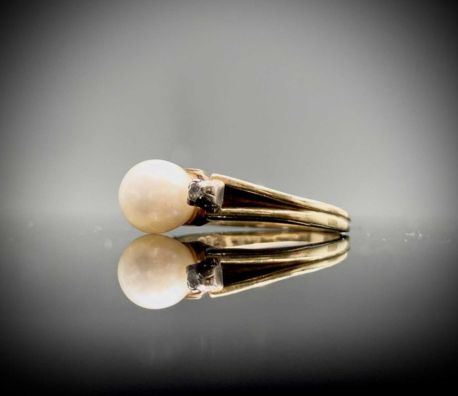 A pretty14ct ring, set a pearl with two tiny diamonds.Marked 585.