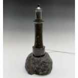 A Cornish serpentine table lamp, modelled as a lighthouse on a naturalistic rocky base cut with