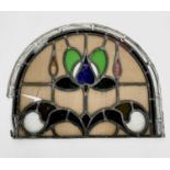 An early 20th century leaded and stained glass panel of arched form. Height 45cm, width 59cm.