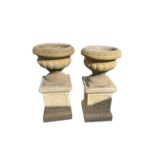 A pair of 'Sandford Stone' garden urns on pedestals. Height 78cm.