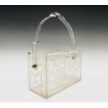 A 1950s clear lucite box handbag, having carved floral decoration. Height 11.5cm (24.5cm when handle