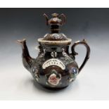 A Victorian Measham treacle glazed bargeware teapot, dated 1884, with teapot finial, applied with