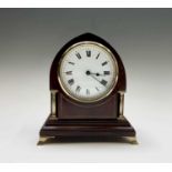 An Edwardian mahogany and inlaid mantel timepiece, of arched shape and with brass side columns and