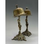 A pair of early 20th century brass counter service bells cast with cherubs. Height 24cm.