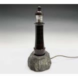 A Cornish serpentine table lamp, modelled as a lighthouse on a naturalistic rocky base. Height