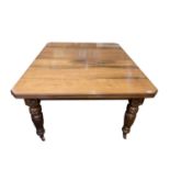 A late Victorian walnut extending dining table, raised on turned fluted legs and castors, height