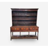 A George III oak dresser, the rack with three shelves, the lower part with three drawers on ring