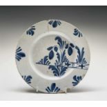 An English delft plate, 18th century, painted in blue with floral decoration and a garden fence,