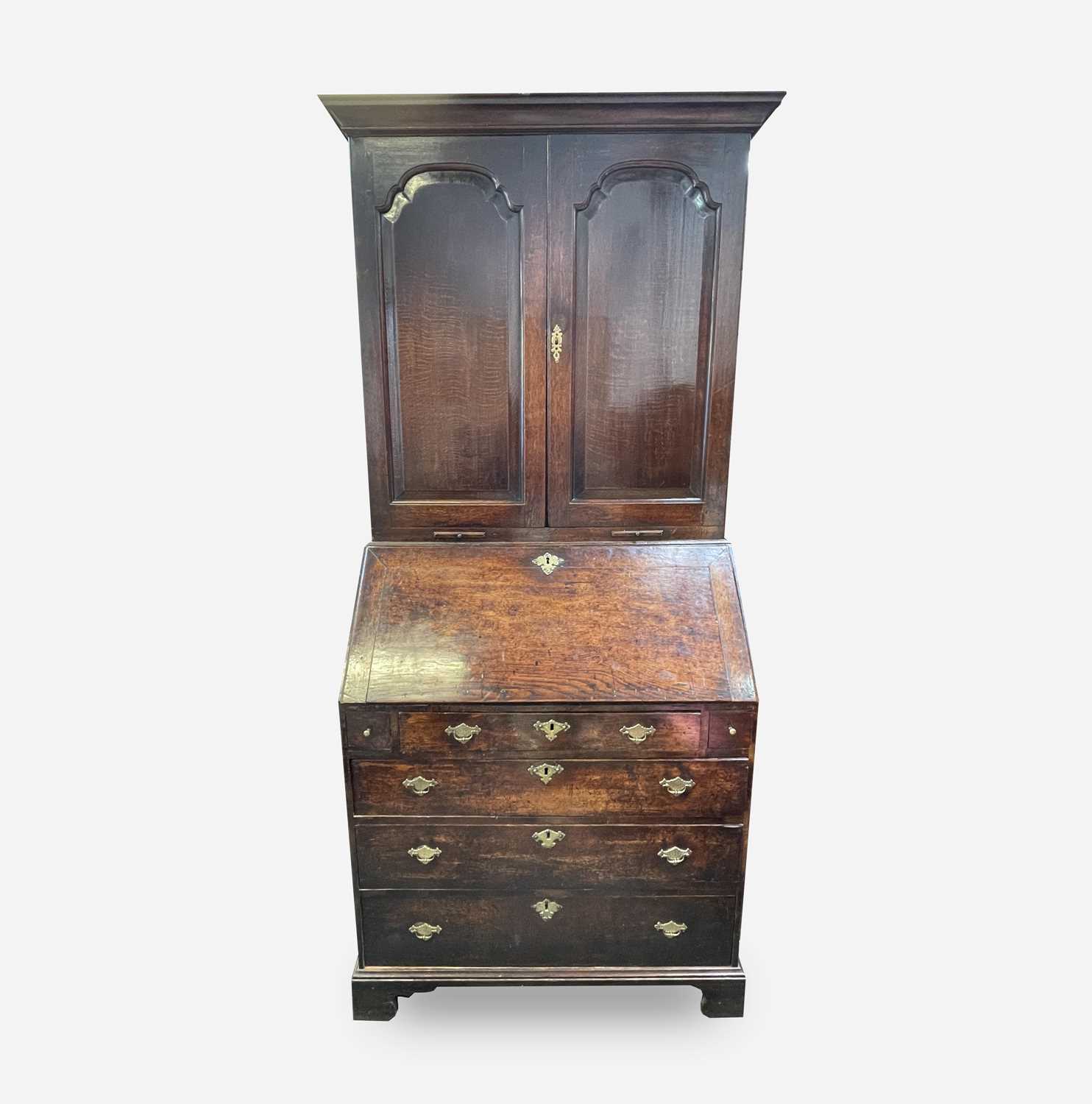 A George III oak bureau bookcase, with a pair of arched panelled doors opening to reveal shelves and