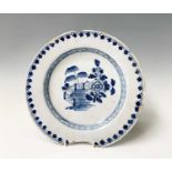 An English delft dish, circa 1760, painted in blue with a pseudo-Chinese fenced flowering garden,