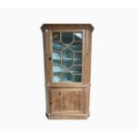 A 19th century pine standing corner cupboard, the astragal glazed doors enclosing four shaped