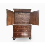 An early 18th century walnut cabinet on chest, with feather banding throughout, the cushion