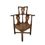 A George III oak corner armchair, with headrest and three pierced splats and three turned pillars,