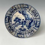 A Delft blue and white charger, 18th century, decorated with a figure in a garden setting,