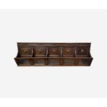 An oak wall mounted stationery rack, circa 1900, the five sections each with a lozenge motif and