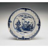 An English Delft plate, mid 18th century, painted in blue with foliage within a fenced garden,
