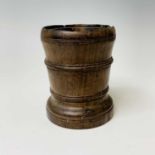 An 18th century treen mortar, with ring turned cylindrical body, height 11.5cm, diameter 9cm.