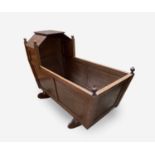 An elm crib, early 20th century, with a panelled body, the canopy surmounted by turned finials,