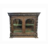 A Victorian carved oak display cabinet, with glazed doors and sides, carved with lion masks,fruit