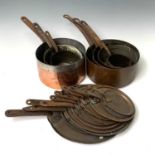 Seven Victorian copper pans, each with iron handles and eleven lids.
