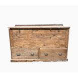 A pine chest, early 20th century, with a hinged fall front above two drawers and a plinth base,