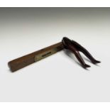 A treen nutcracker, circa 1900, formed as a pair of legs, length 17.5cm, width 4cm and a brass
