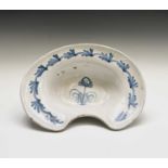 A tin glazed barber's bowl, 18th century, painted with a blue stylised plant to the centre, height