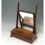 An early 18th century figured walnut toilet mirror, the rectangular mirrored plate above three
