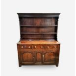 A George III oak dresser, North/Mid Wales, the rack with a moulded cornice above two shelves, the